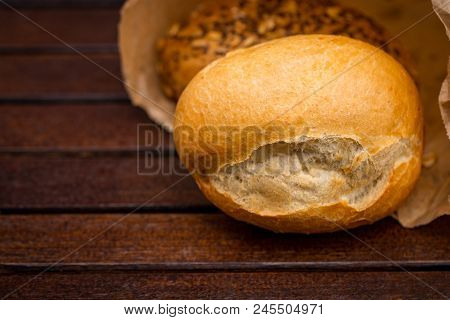 Fresh Baked Bread Wrapped In Paper, On Wooden Background
