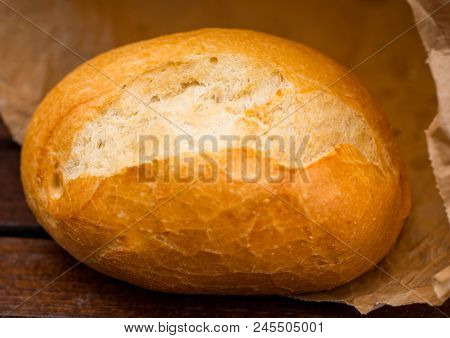 Fresh Baked Bread Wrapped In Paper, On Wooden Background