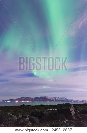 Green Aurora Borealis Over A Black Sand Beach, The Ocean, And Mountains Outside Reykjavik, Iceland