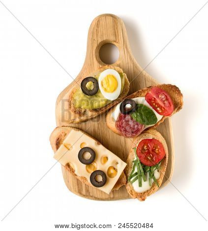 Open faced sandwich canape or crostini on a wooden serving board isolated on white background closeup. Top view.