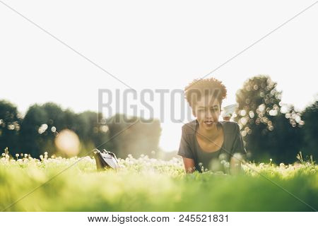 View From The Ground Level Of A Sunny Glade With Beautiful Happy African-american Girl Laying On In 
