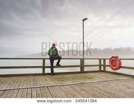 Man In Hat With Backpack Travelling, Tourist On Bridge Watch To The Sea. Lowcost  Travel