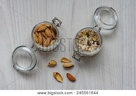Still Life Of Healthy Food And Diet Food, Almonds And Muesli In Glass Jars On A Wooden Background.