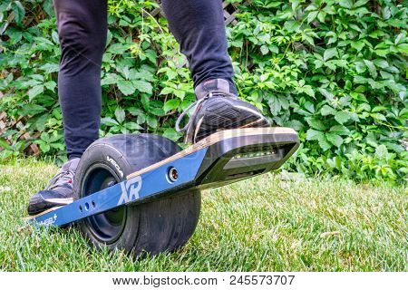 Fort Collins, CO, USA - June 16, 2018: Starting a ride on Onewheel, a self-balanced electric skate board (+XR model) by Future Motion on grass in a backyard.