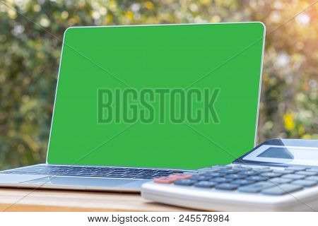 Mock Up Image Of Laptop With Blank Green Screen And Calculator Near By On Wooden Table Outdoor With 