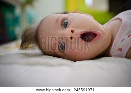 Portrait Of A Baby Laying On The Bed With A Surprised Expression Of Utter Consternation On Her Face.