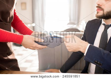 Close-up Of Bearded Businessman In Suit Paying For Lunch And Putting Credit Card On Card Reader Whil