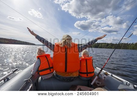Girl In A Life Jacket Floating On The Boat With His Hands Up. Children In Life Jackets Sitting Next
