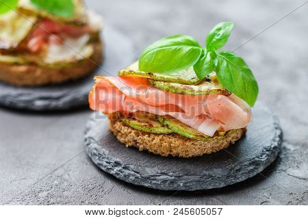 Mini Ham  (hamon, Prosciutto) Sandwiches, Fried Zucchini And Basil Close-up On Black Surface. Gourme