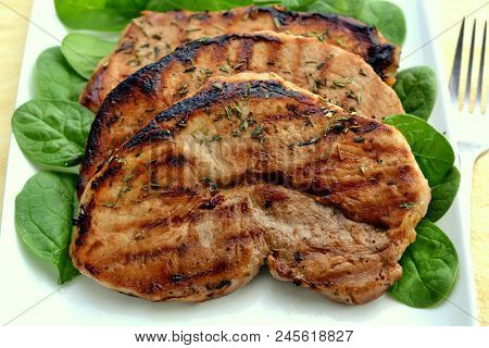 Grilled Center Cut Pork Chop: Served On A Bed Of Baby Spinach Leaves