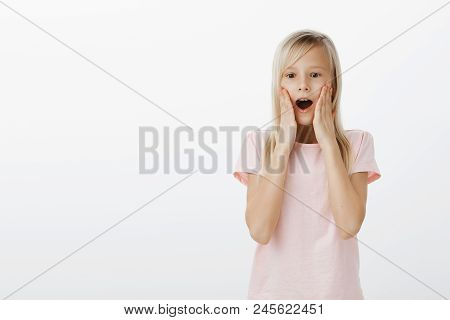 Indoor Shot Of Pleased Surprised Adorable Girl With Curious Amazed Expression, Dropping Jaw And Sayi