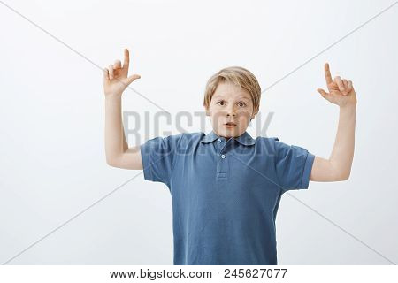 Portrait Of Impressed Excited Young European Boy With Blond Hair, Raising Index Fingers And Pointing