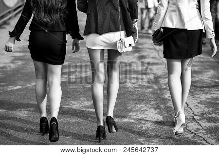 Epilation Of The Legs. Female Legs Of Three Young Girls On High Heels Walking In Street Sunny Day Wi