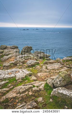 Large Boulders On The Coast And Small Lighthouse On The Background In The Lands End - The Most Weste