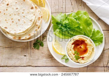 Hummus With Olive Oil And Paprika, Served With Pita, Lemon And Lettuce Leaves. Selective Focus.