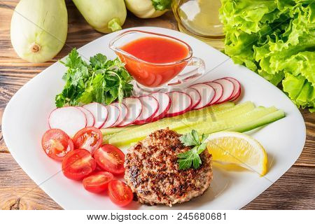 Chopped Steak Cutlet Cooked On Grill On White Plate With Assorty Mix Vegetables Radish Cherry Tomato
