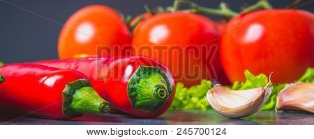 Red Chili Peppers, Tomatoes, Sadat And Garlic On A Gray Marble Background