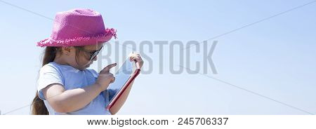 Little Girl With A Tablet Computer In Hands. Good Summer Weekend On The Beach. Copy Spce