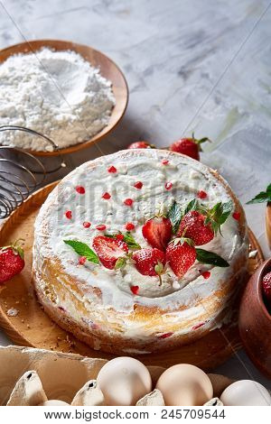 Strawberry Tart Covered With Whipped Sour Cream Surrounded By Organic Ingredients Over White Backgro