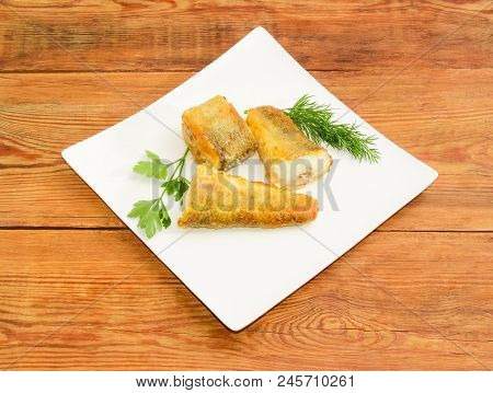 Three Slices Of The Fried Saltwater Fish Notothenia With Parsley And Dill Twigs On A White Square Di