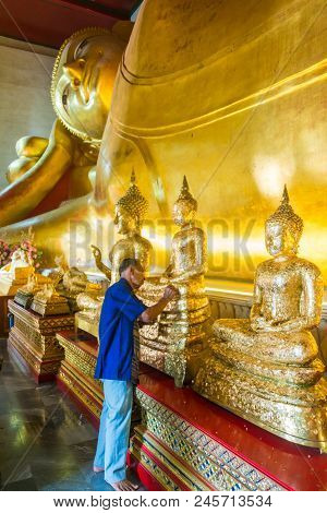 Phetchaburi, Thailand - March 11, 2018: Old Buddhist Man Gilding On The Knee Of Golden Buddha Image 
