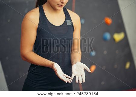 Young Unrecognizable Woman In Black Shirt With Chalked Hands Posing At Indoor Climbing Gym Wall