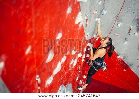 High Angle View Of Sporty Brown-haired Woman Exercising Wall Climbing On Colorful Red Artificial Roc