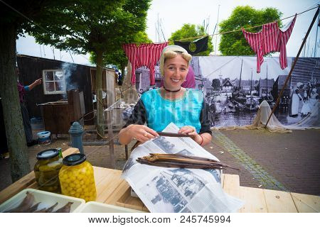 Urk, Netherlands - May 19, 2018: Unknown Woman In Traditional Clothes Selling Smoked Eel On The Annu