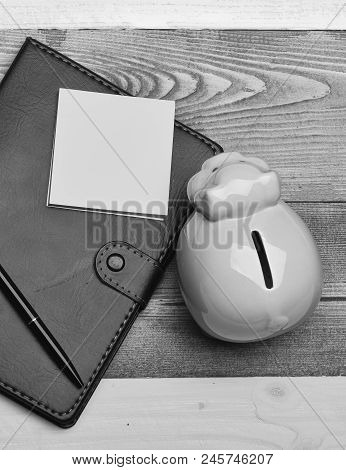 Piggy Bank In Pink Color On Colorful Wooden Background. Moneybox With Pig Face Near Organizer And Pe