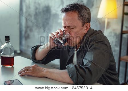 Concerned Man. Concerned Mature Man Feeling Extremely Stressed Drinking Some Alcohol After Big Famil