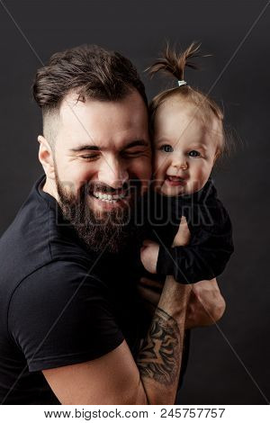 Portrait Of Well Groomed Tattooed Father Passionatly Embracing His Amasing Little Baby Girl With Fun