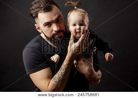 Father And Infant Daughter Posing With Different Funny Grimaces At Studio Black Background With Copy