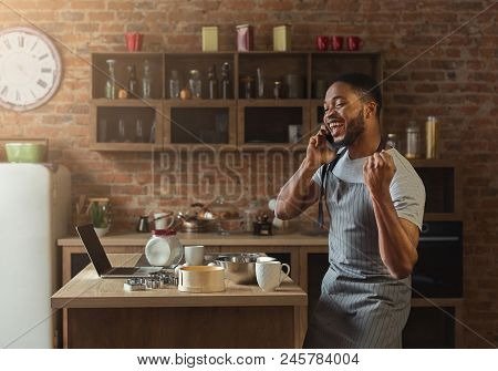 Happy African American Man Talking On Smartphone While Baking In Kitchen