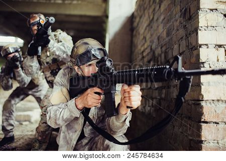 A Picture Of Guy Looking For An Aim. He Is Loooking Through Loop Gun. He Is Concentrated. There Are 