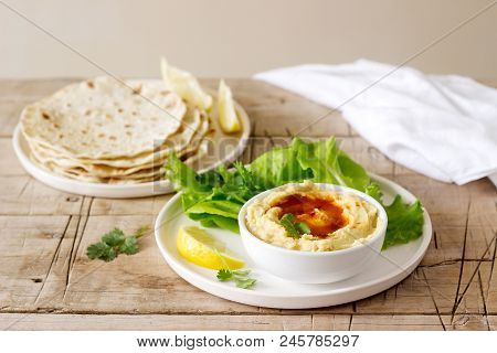 Hummus With Olive Oil And Paprika, Served With Pita, Lemon And Lettuce Leaves. Selective Focus.