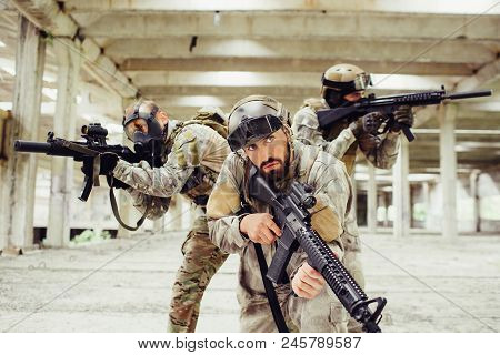 Three Warriors Are Posing. Two Of Them Is Looking To Different Sides And Taking Aim Through Rifle Le