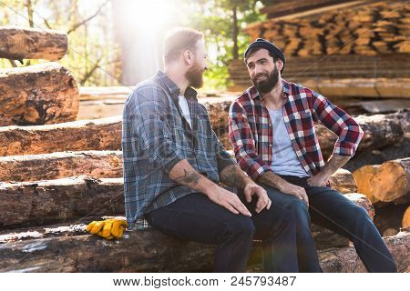Two Smiling Bearded Lumberjacks Talking To Each Other At Sawmill