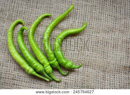 Five Long, Sharp Green Peppers On A Brown Background. Combustion. Mexican Condiments. Organic Food.