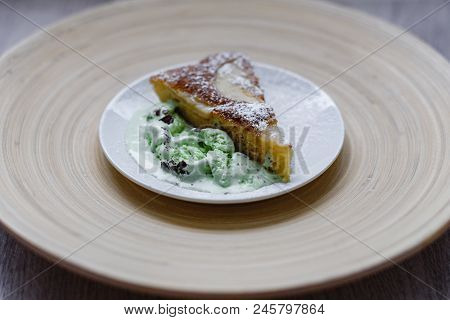 A Piece Of Apple Pie With Pistachio Ice Cream On A Background Of A Bamboo Plate In A White Plate.
