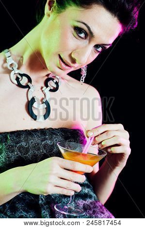 Young Caucasian Brunette Taking Aperitif With Black Background. Studio Shot