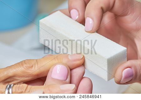 Senior Woman Receiving Manicure In Beauty Salon. Professional Beautician Takes Care Of Senior Woman 