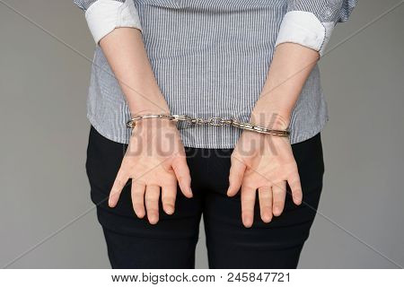Close-up. Arrested Woman Handcuffed Hands At The Back Isolated On Gray Background. Prisoner Or Arres