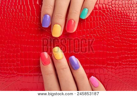 Multicolored Manicure And Red Lacquered Background. Female Fingers With Colorful Summer Nail Polish 