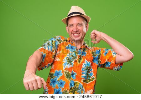Studio Shot Of Mature Tourist Man Ready For Vacation Against Chroma Key With Green Background
