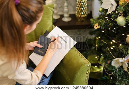 Girl Filling Visa Application Form, Student Sitting On Grey Chair With Passport. Young Fair-haired W
