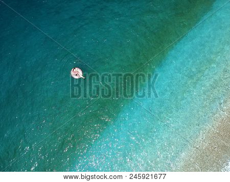 Aerial View Young Woman On Giant Inflated Flamingo Float In Turquois Water Of Ionian Sea Albania.