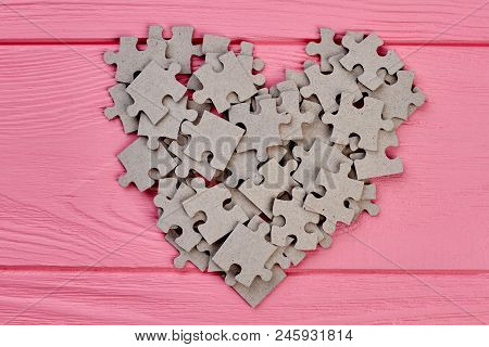 Shape Of Heart From Cardboard Puzzles. Grey Jigsaw Puzzles Forming Shape Of Heart On Colorful Wooden
