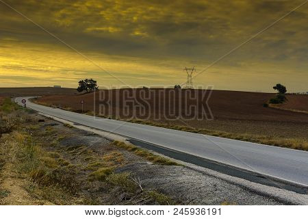 Asphalt Road Between Hills Covered With Fields In Spain At Sunrise. Prohibitory Traffic Sign No Over