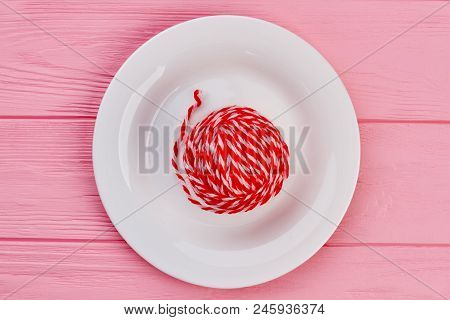 Ball Of Yarn On White Plate. Ball Of Red Woolen Thread On Porcelain Plate, Top View.