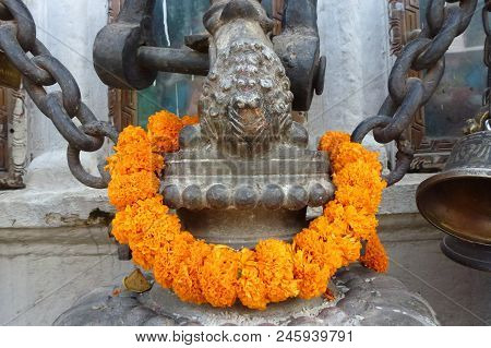 Statue With A Garland Made With Orange Flowers At The Boudhanath Stupa, Kathmandu, Nepal